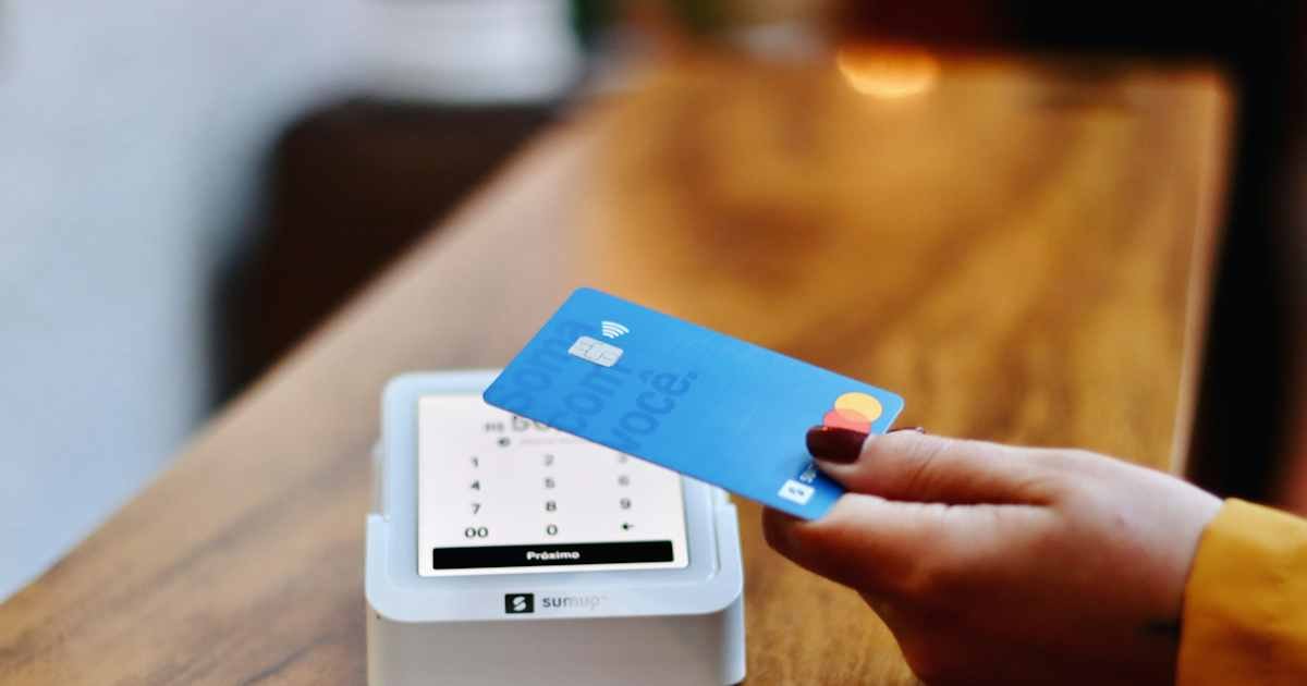 What Does SQ Mean on a Credit Card Charge? 1 Customer holding a credit card near a contactless payment terminal