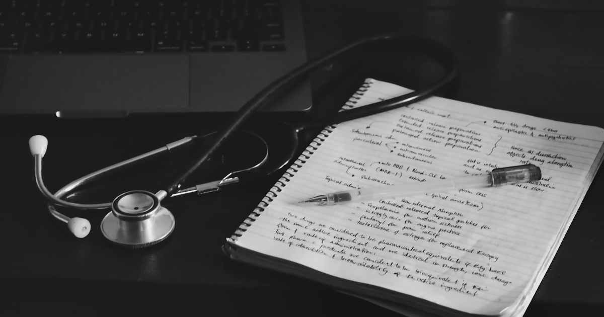 Notebook and stethoscope next to laptop illustrating nursing school billing